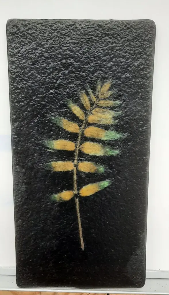 A Vitra Fossil Panel Class plate with a yellow leaf on it.