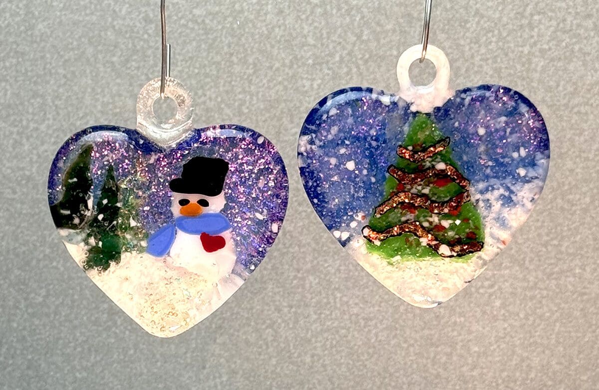 Heart-shaped holiday ornaments featuring a snowman and a Christmas tree.